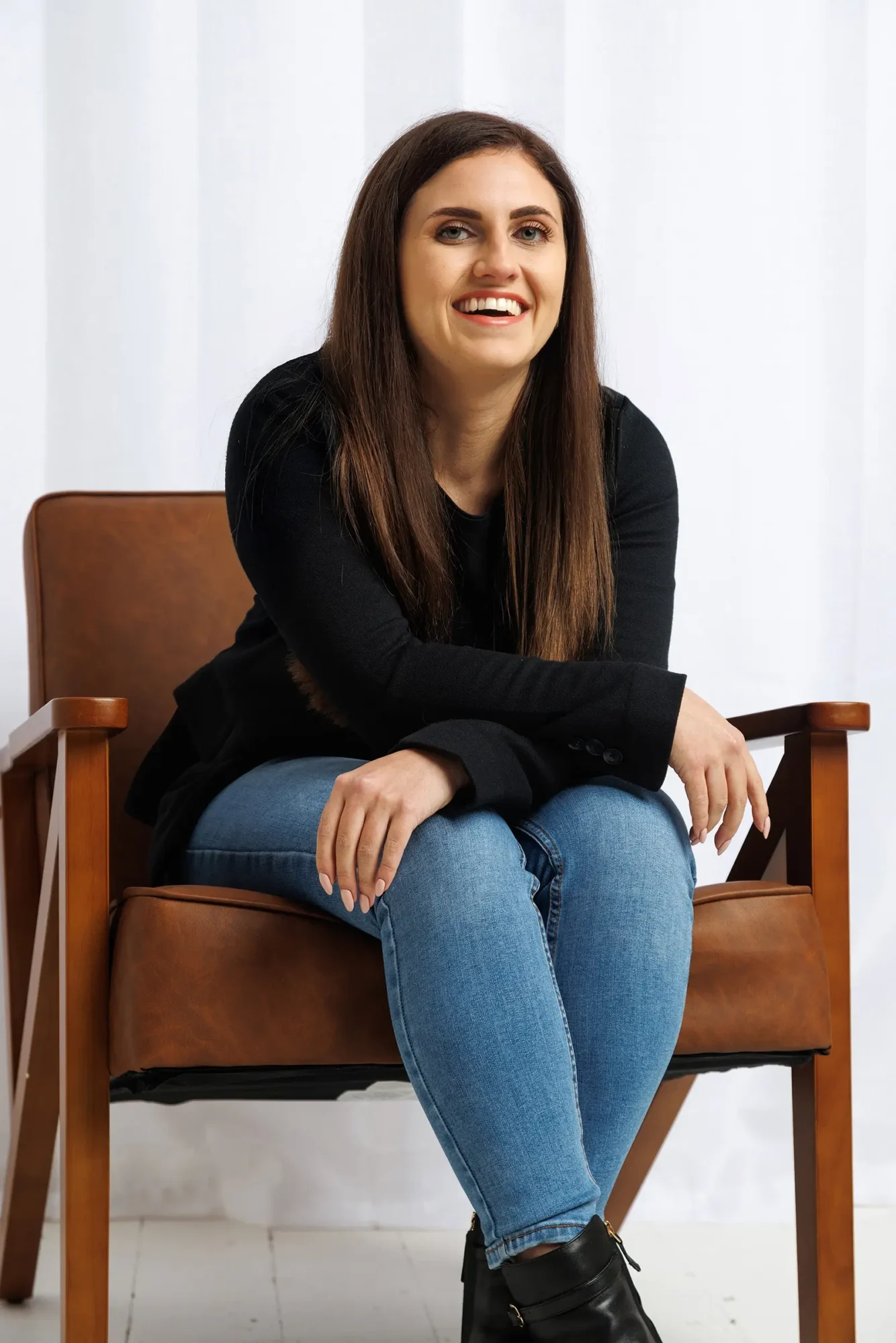 Nicole Rogers from digital bear studio sitting in a large brown chair in design agency berkshire smiling against a white background